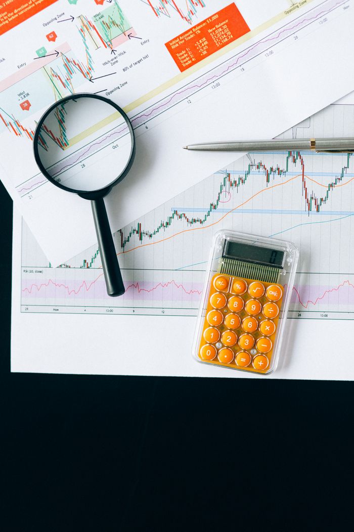 Offerings Close-up of financial documents with charts, calculator and magnifying glass for analysis.